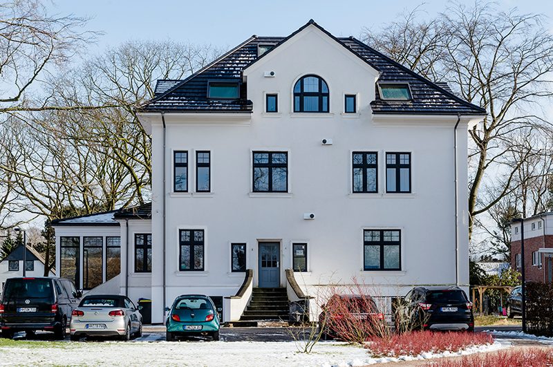 Sanierte weiße Stadtvilla mit Rundbogenfenster im Winter