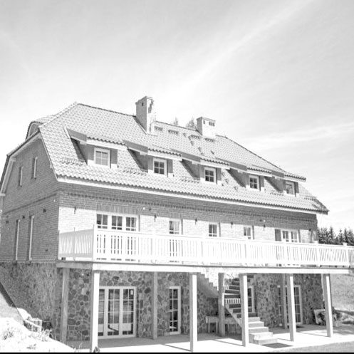 Ferienhaus mit Mansarddach, Feldsteinsockel und Holzbalkon