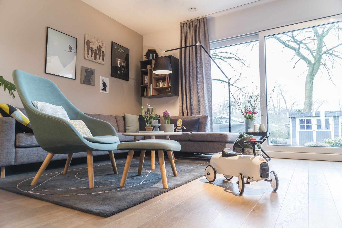 Helles Wohnzimmer mit großen Fenstern, Sesseln und Teppich