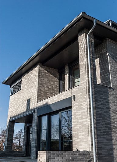 Fassade aus grauem Klinker mit großen Fenstern